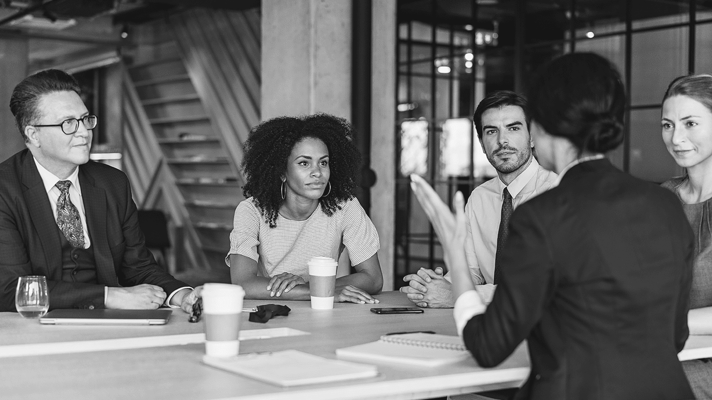 Several people sitting around a table with coffee
