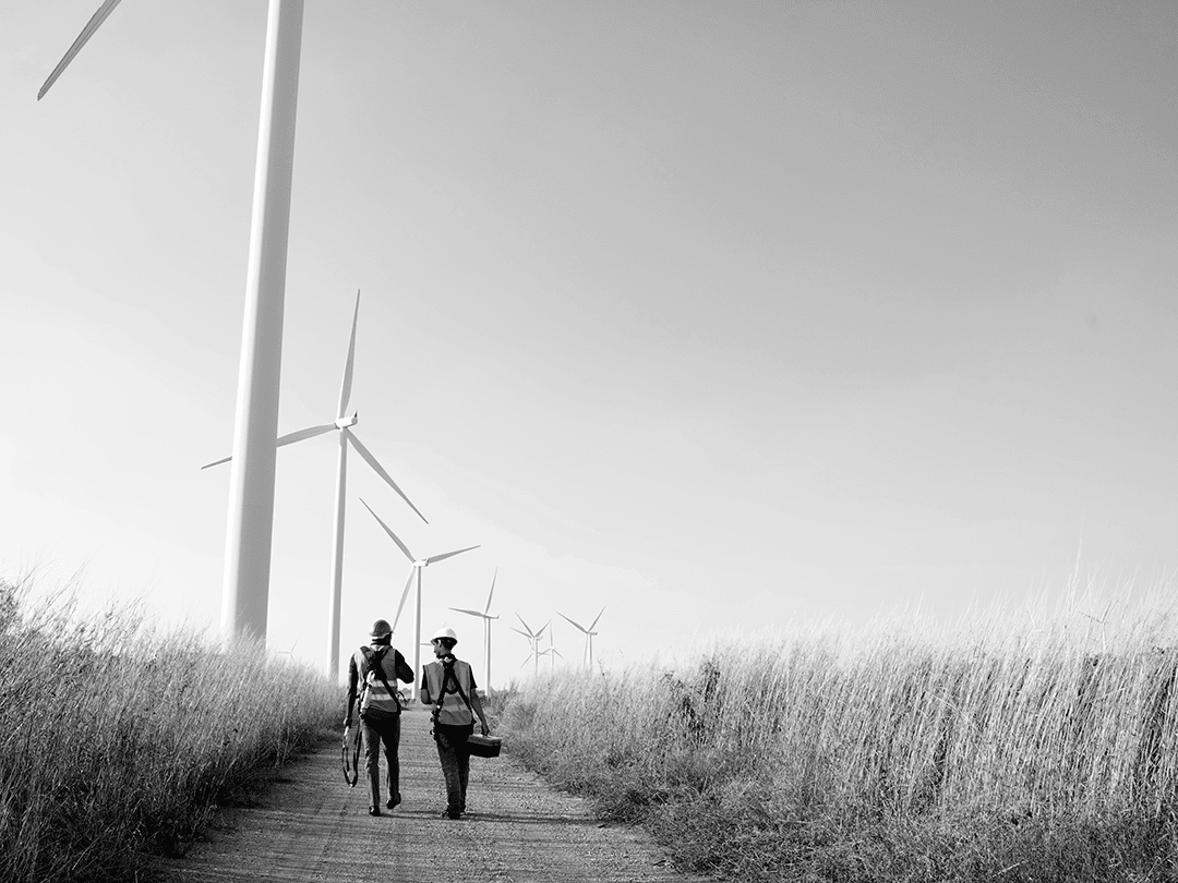 Two people walking near wind turbines