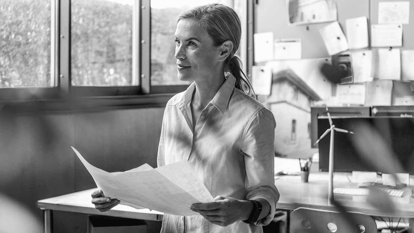 Woman reading files at work and staring into space